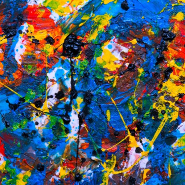 A close-up of an abstract painting: thick red, blue, yellow, and black paint splattered and layered across textured canvas.